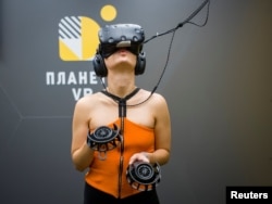 A visitor uses virtual reality glasses during the presentation of a simulator showing the 2013-14 demonstration in Ukraine, when dozens of protesters were killed in the final moments of Viktor Yanukovich's rule, in Kyiv, Ukraine, Sept. 12, 2018.