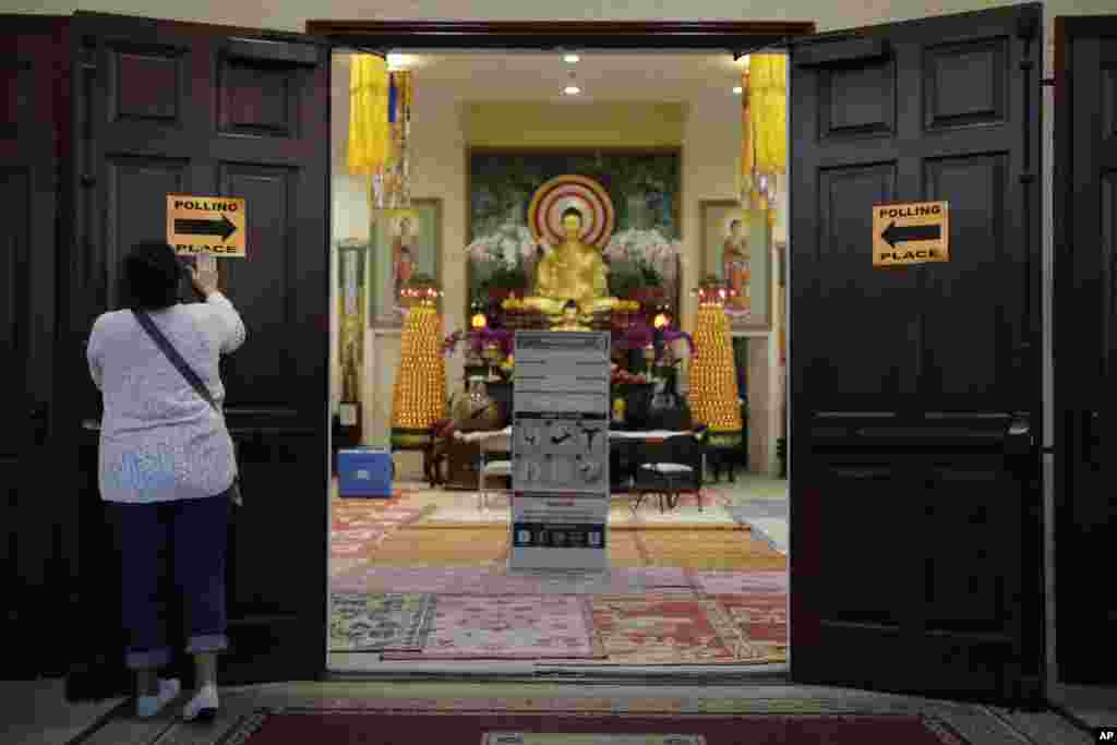 អ្នកធ្វើការស្ម័គ្រចិត្តក្នុងការិយាល័យបោះឆ្នោត អ្នកស្រី Mary Roca អាយុ ៥១ឆ្នាំ បិទប័ណ្ណនៅលើទ្វាព្រះវិហារ Chua Phat To Gotama មុនពេលបោះឆ្នោតកាលពីថ្ងៃអង្គារ ទី៨ វិច្ឆិកា ឆ្នាំ ២០១៦ ក្នុងទីក្រុង Long Beach រដ្ឋកាលីហ្វ័រញ៉ា។ (រូបភាព៖ AP/ Jae C. Hong)
