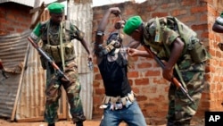 Rwandan peacekeepers remove lucky charms from a suspected anti-Balaka Christian carrying a rifle and a grenade in a Muslim market in Bangui.