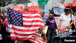 Protesters burn a U.S. flag and a mock flag with pictures of U.S. President-elect Donald Trump outside the U.S. embassy in metro Manila, Philippines, Jan. 20, 2017. 