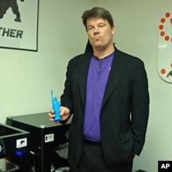 David Cox holding a Statue of Liberty figure made by a 3D printer