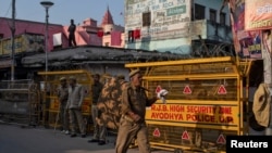 Seorang perwira polisi berjalan melewati barikade keamanan ketika yang lain berjaga di dekat sebuah kuil setelah putusan Mahkamah Agung mengenai situs keagamaan yang disengketakan, di Ayodhya, India, 10 November 2019. (Foto: Reuters/Danish Siddiqui)