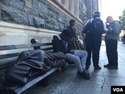 A man rests next to a statue of the homeless Jesus outside Catholic Charities in Washington. (K. Gypson/VOA)