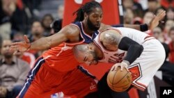 Nene, de los Wizards (de rojo) obstaculiza a Carlos Boozer, de los Chicago Bulls, durante el primer juego de los playoffs de la NBA, que ganaron los primeros, 102 a 93.