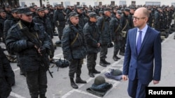 FILE - Ukrainian Prime Minister Arseniy Yatsenyuk (R) inspects servicemen and government defence forces outside Kyiv, Sept. 30, 2014.