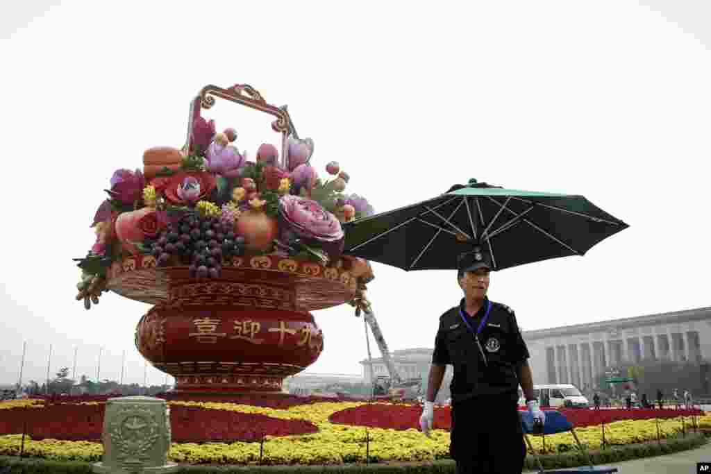 A security officer stands watch near a giant basket decorated with replicas of flowers and fruits on display at Tiananmen Square in Beijing.