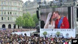 Royal supporters watch Britain's Prince William kissing his wife Kate, Duchess of Cambridge on a giant screen in Trafalgar Square in central London, after the wedding ceremony, on April 29, 2011.