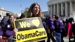 FILE - Holding a sign saying "We Love ObamaCare," a supporter of health care reform rallies in front of the Supreme Court in Washington, D.C., March 27, 2012.