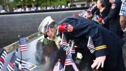 Retired Paramedic Chief Charlie Wells kisses the name of a relative killed in the attack on the World Trade Center at the National September 11 Memorial in New York on the 20th anniversary of the attacks, Sept. 11, 2021.