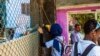 A school girl passes a bottle of juice to her colleague from the street before classes start Sept. 16, 2017, at the African Hope School in Cairo, Egypt.