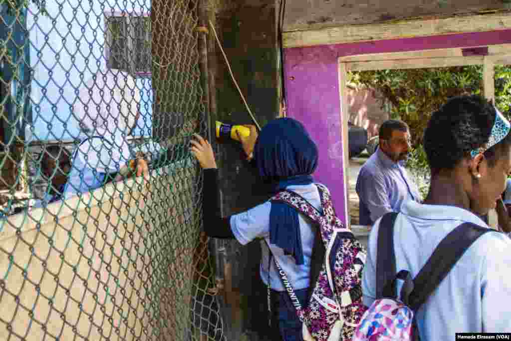 A school girl passes a bottle of juice to her colleague from the street before classes start Sept. 16, 2017, at the African Hope School in Cairo, Egypt.