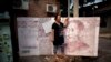 一位女士在北京站在一個巨大的人民幣百元鈔藝術作品前留影。 （2011年8月26日資料照）