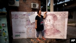 一位女士在北京站在一個巨大的人民幣百元鈔藝術作品前留影。 （2011年8月26日資料照）