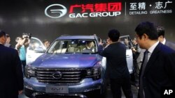 Journalists stand by as Chinese officials examine the Chinese automaker GAC's GS8 SUV after it was unveiled at the Beijing International Auto Show in Beijing, April 25, 2016.