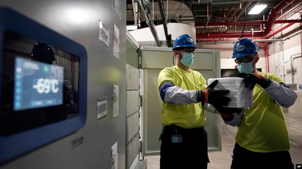 The temperature on a freezer reads -69 degrees Celsius as workers move boxes containing the Pfizer-BioNTech COVID-19 vaccine to be shipped at the Pfizer Global Supply Kalamazoo manufacturing plant in Portage, Mich., Sunday, Dec. 13, 2020. 