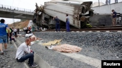 A wounded victim sits next to a body covered with a blanket after a train crashed near Santiago de Compostela, northwestern Spain, July 24, 2013.
