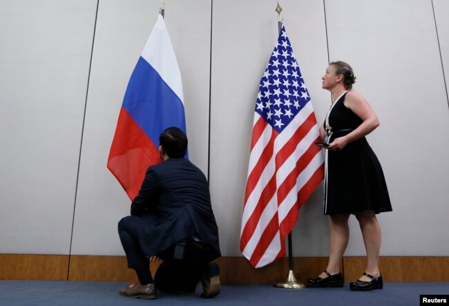 FILE - Staffers install U.S. and Russian flags as part of a bilateral meeting, Aug. 26, 2016. Theoretically, U.S. President Donald Trump and Russian President Vladimir Putin would have an opportunity to meet Friday in Vietnam but it's not clear whether substantive talks will be scheduled.