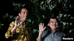 Indonesian president-elect Joko Widodo (l) and his running mate Jusuf Kalla wave to the media at a press briefing in the garden of his home in Jakarta, Aug. 21, 2014.