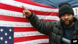 Jamine Clark points to the name of his brother, Jamar Clark, on an upside-down flag bearing names of people killed at the hands of police, outside the Minneapolis Police Department's Fourth Precinct, Nov. 17, 2015, in Minneapolis.