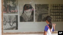 FILE - A Cambodian girl looks at images of Khmer Rouge victims at Tuol Sleng genocide museum, formerly the regime's notorious S-21 prison in Phnom Penh, Cambodia, March 26, 2015.