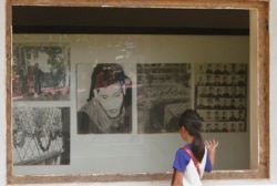 FILE - A Cambodian girl looks at images of Khmer Rouge victims displaying at Tuol Sleng genocide museum, formerly the regime's notorious S-21 prison in Phnom Penh, Cambodia, March 26, 2015.