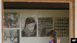 FILE - A Cambodian girl looks at images of Khmer Rouge victims displaying at Tuol Sleng genocide museum, formerly the regime's notorious S-21 prison in Phnom Penh, Cambodia, March 26, 2015.