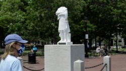 A passer-by walks near a damaged Christopher Columbus statue, Wednesday, June 10, 2020, in a waterfront park near the city's traditionally Italian North End neighborhood, in Boston.