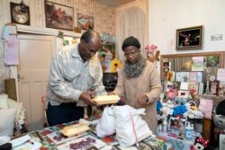 Sylius, left, and Bridgette Toussaint unpack their meals prepared by members of the Preston Windrush Covid Response team, in Preston, England, Friday Feb. 19, 2021. (AP Photo/Jon Super)