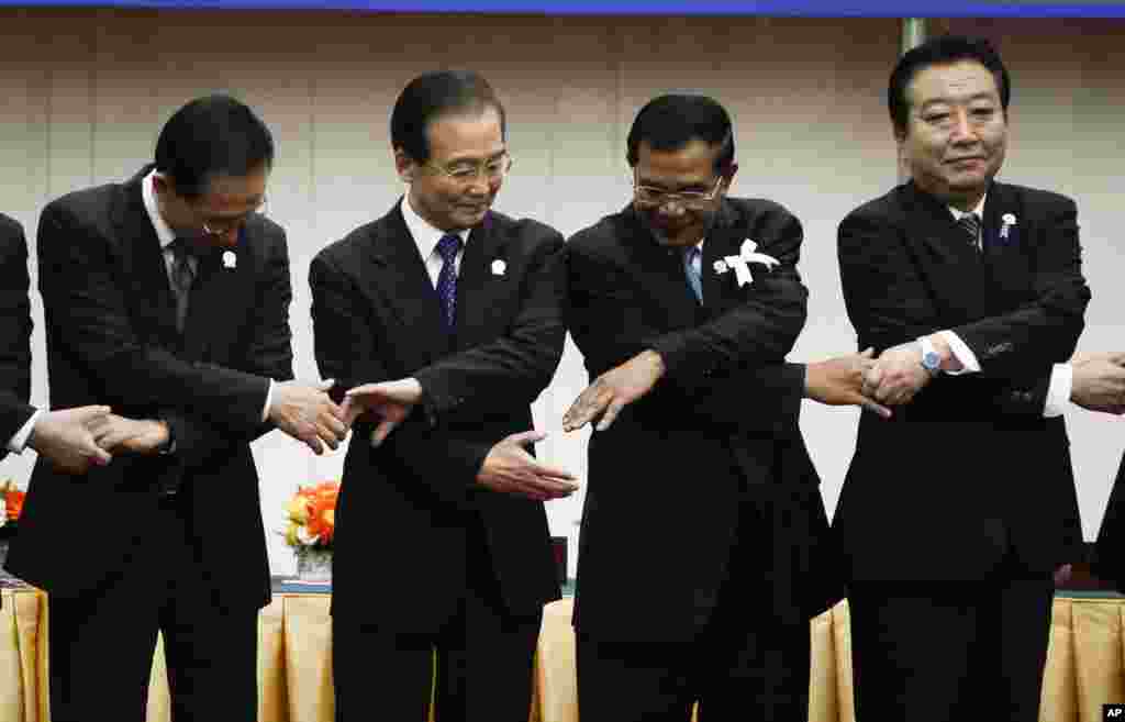 From left: South Korea&#39;s President Lee Myung-bak, China&#39;s Premier Wen Jiabao, Cambodia&#39;s Prime Minister Hun Sen and Japan&#39;s Prime Minister Yoshihiko Noda prepare to join hands together for a group photo during the ASEAN Plus Three (APT) Commemorative Summit in Phnom Penh, Cambodia, Monday, Nov. 19, 2012. (AP Photo/Vincent Thian)