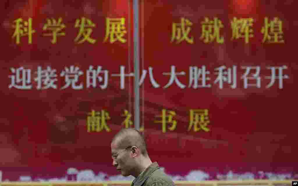 Seorang pria melewati propaganda resmi menyambut kongres di sebuah toko buku di Shanghai (8/11).&nbsp;