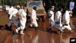 Volunteers, wearing protective gear, walk across a street covered by toxic red sludge in Devecser, Hungary, 11 Oct 2010