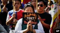 FILE - Exiled Tibetans pray during a protest rally to express solidarity with Tibetans who have self-immolated, in New Delhi, India, Nov. 28, 2012.