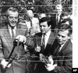 Hungarian Foreign Minister Gyula Horn (r) with Austrian counterpart Alois Mock cut through barbed wire of former Iron Curtain marking border between East, West in Sopron, Hungary, 27 Jun 1989