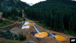 FILE - Water flows through a series of retention ponds built to contain and filter out heavy metals and chemicals from the Gold King mine chemical accident, in the spillway about 1/4 mile downstream from the mine, outside Silverton, Colorado, Aug. 12, 201