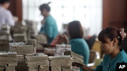 Workers count Burma's kyat banknotes at the office of a local bank in Rangoon, April 2, 2012. 