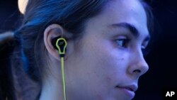 FILE - A young woman is seen wearing headphones at the Consumer Electronics Show in Las Vegas Jan. 6, 2015.