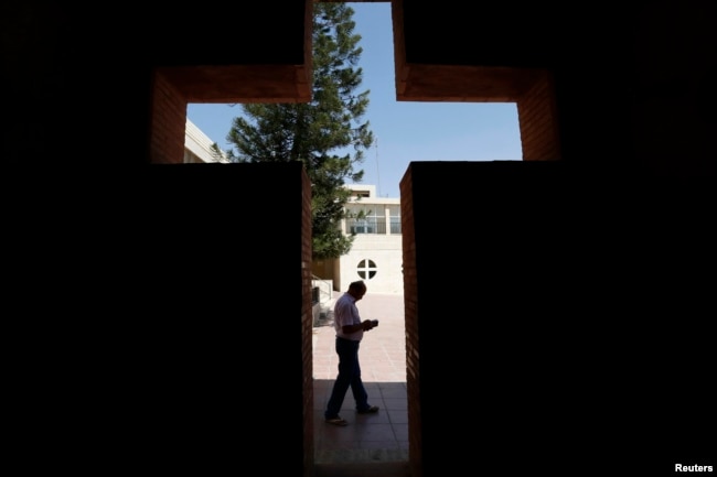 FILE - An Iraqi Christian man from Mosul, who fled with his family from violence in their country, reads a book at the Latin Patriarchate Church in Amman, Jordan, Aug. 21, 2014.