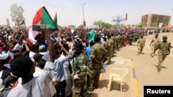 Sudanese military officers control demonstrators as they protest against the army's announcement that deposed president Omar al-Bashir would be replaced by a military-led transitional council, near Defense Ministry in Khartoum, Sudan, April 12, 2019.