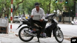 Nguyen Kim Lan reads a newspaper as he waits for customers at an intersection in Hanoi, Vietnam, June 21, 2017. Lan, 62-year-old traditional motorbike taxi driver, or Xe Om, used to make a decent living shuttling customers, but his clientele has dwindled as young and tech-savvy Vietnamese increasingly use ride-hailing apps.