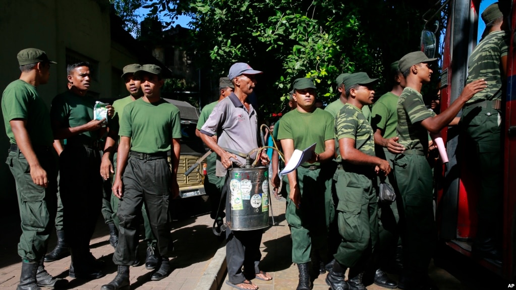 FILE - A Sri Lankan municipal worker, center, along with army soldiers leave for Dengue fever eradication work in Colombo, Sri Lanka, July 4, 2017. 