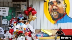 Un enfant est assis à côté d'un hommage à Alton Sterling, à Baton Rouge en Louisiane, le 7 juillet 2016 