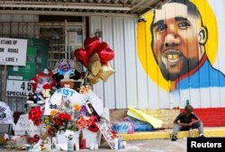 FILE - A boy sits next to a makeshift memorial outside the Triple S Food Mart where Alton Sterling was fatally shot by police in Baton Rouge, Louisiana, July 7, 2016.