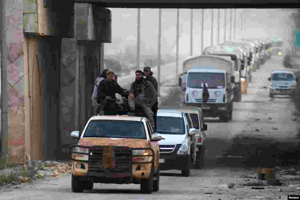 Rebel fighters escort a Syrian Arab Red Crescent aid convoy heading towards the villages of al-Foua and Kefraya in Idlib province, Syria.