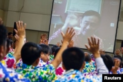 FILE - Opposition Puea Thai party members react as former Thai Prime Minister Thaksin Shinawatra waves to them during a Skype video call at the party headquarters in Bangkok, Thailand, April 7, 2016.
