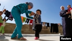 28일 레바논 남부 세바의 시리아 난민촌에서 한 소녀가 소아마비 의심 증세를 보이는 동생을 돕고 있다.
