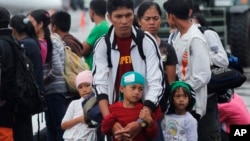 A father and his children who survived the massive Typhoon Haiyan, wait for an evacuation flight on the tarmac of the airport in Tacloban, Philippines, Nov. 21, 2013.