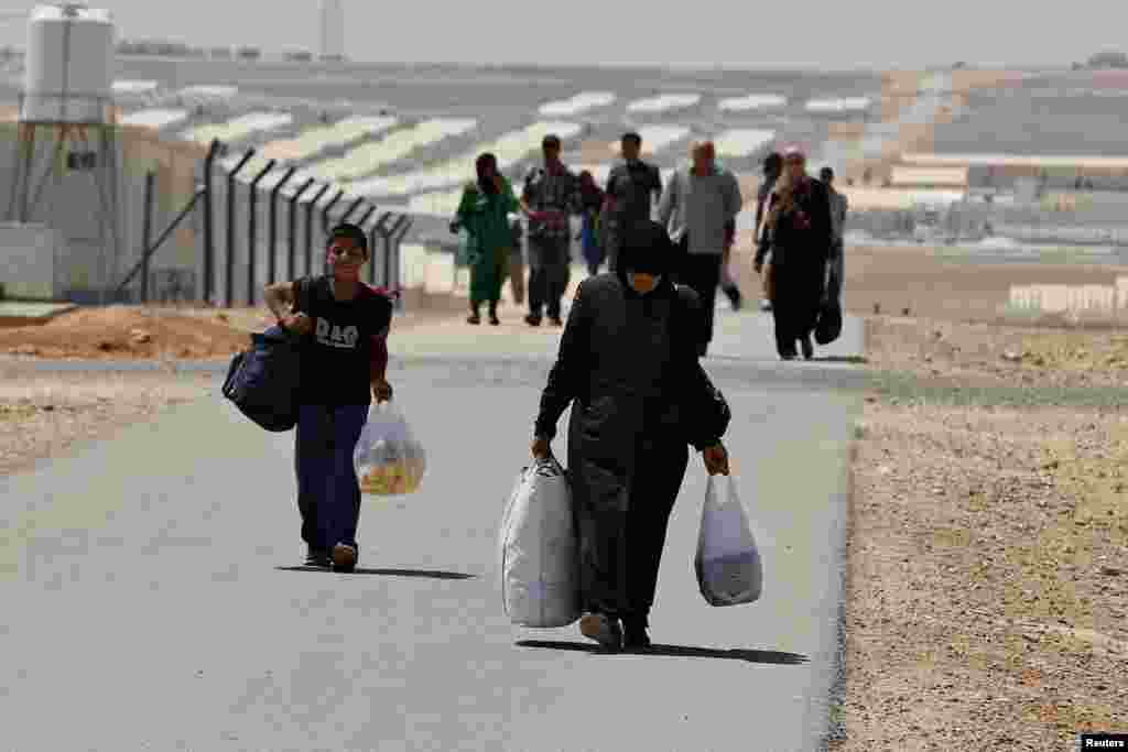 Newly-arrived Syrian refugees carry their belongings as they walk at Azraq refugee camp near Al Azraq area, east of Amman, Jordan, Aug., 2014. 