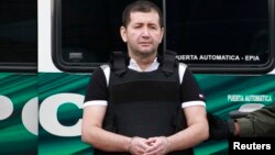 FILE - Colombian drug trafficker Daniel 'El Loco' Barrera, before being extradited to the United States, faces journalists at an airport in Bogota, July 9, 2013.