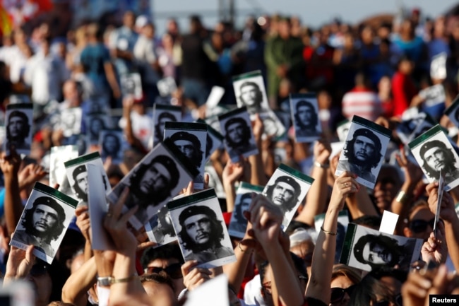People hold images of late Cuban revolutionary hero Ernesto "Che" Guevara during a ceremony commemorating the 50th anniversary of his death, Santa Clara, Cuba, Oct. 8, 2017.