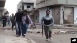 Image made from amateur video purports to show a Syrian rebel helping an injured man in Rastan, Homs, Syria. 